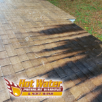 A close-up of asphalt shingles covered in algae being cleaned in Tallahassee using a combination of algaecide and low-pressure (below 60 PSI) water.