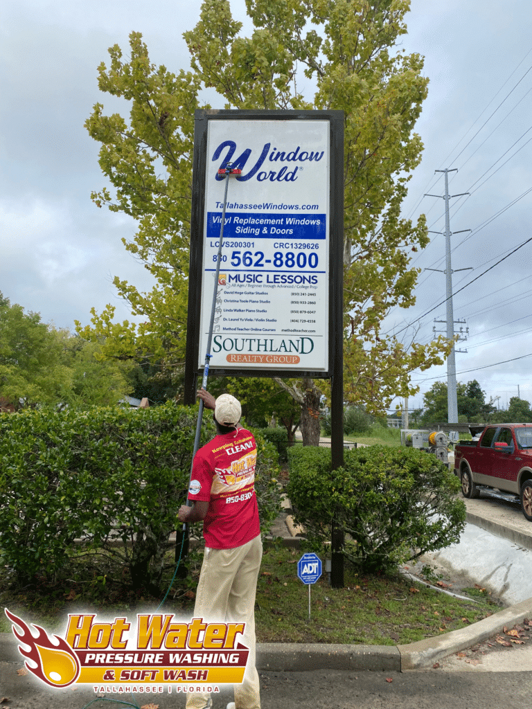 A worker uses a water-fed pole to clean the large "Window World of Tallahassee" sign in front of their office building.