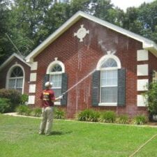 Man washing red brick home.